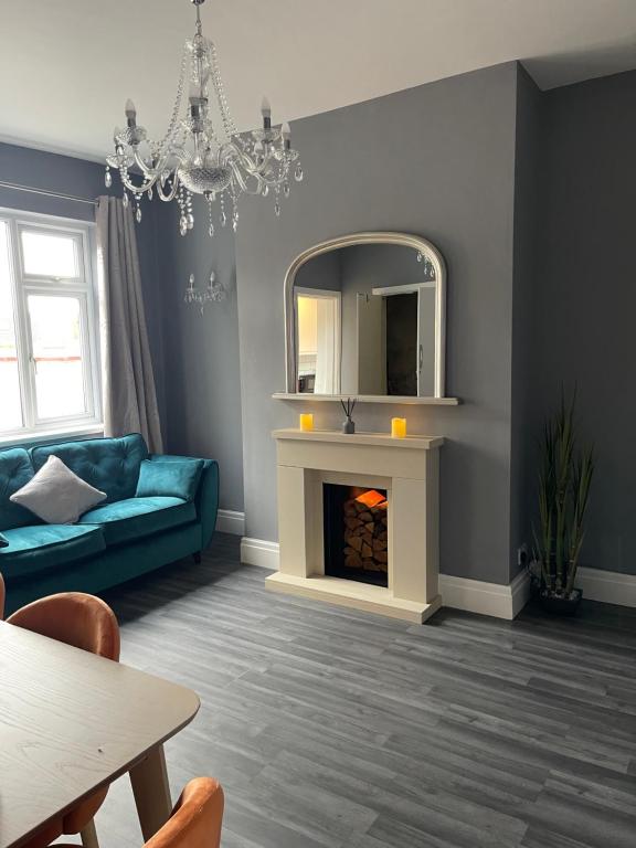 een woonkamer met een blauwe bank en een spiegel bij Moda House Wigan - Beautiful 4 Bed Property in Pemberton