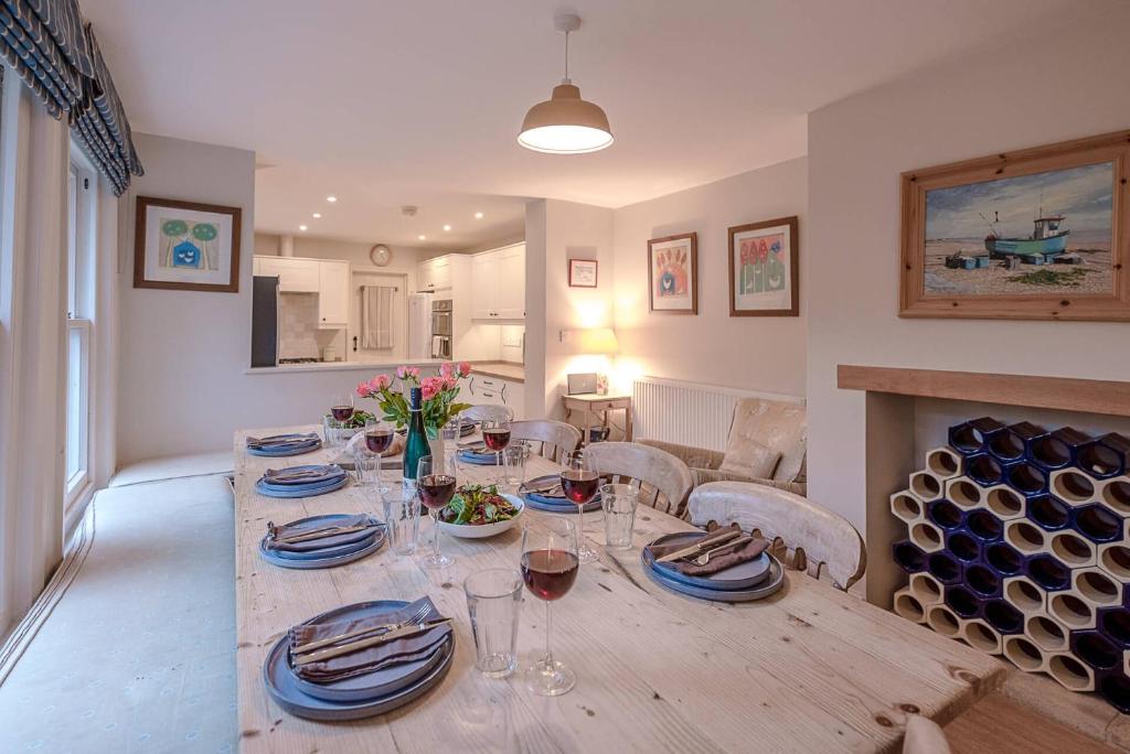 a dining room with a table with plates and wine glasses at 18 Hartington, Aldeburgh in Aldeburgh