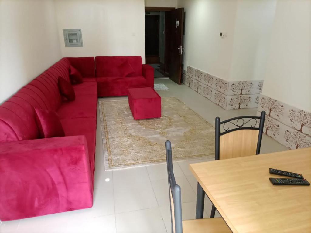 a living room with a red couch and a table at شقة غرفتين وصاله ابراج الؤلؤه in Ajman 