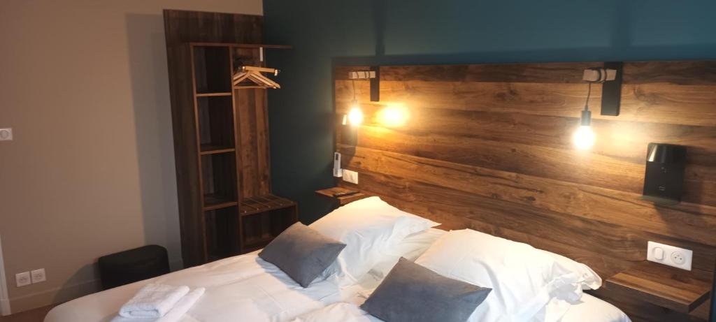 a bedroom with a bed with a wooden headboard at Logis Hôtel Spa la Poste in Vitry-le-François