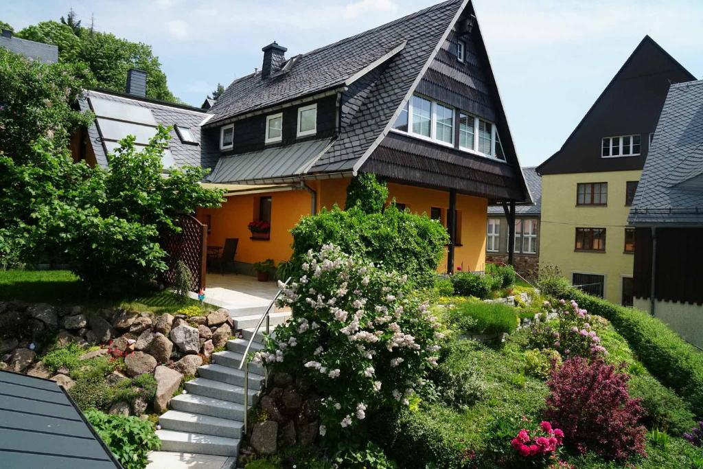una casa amarilla con techo negro y algunas flores en Ferienwohnung Splitek, en Kurort Altenberg