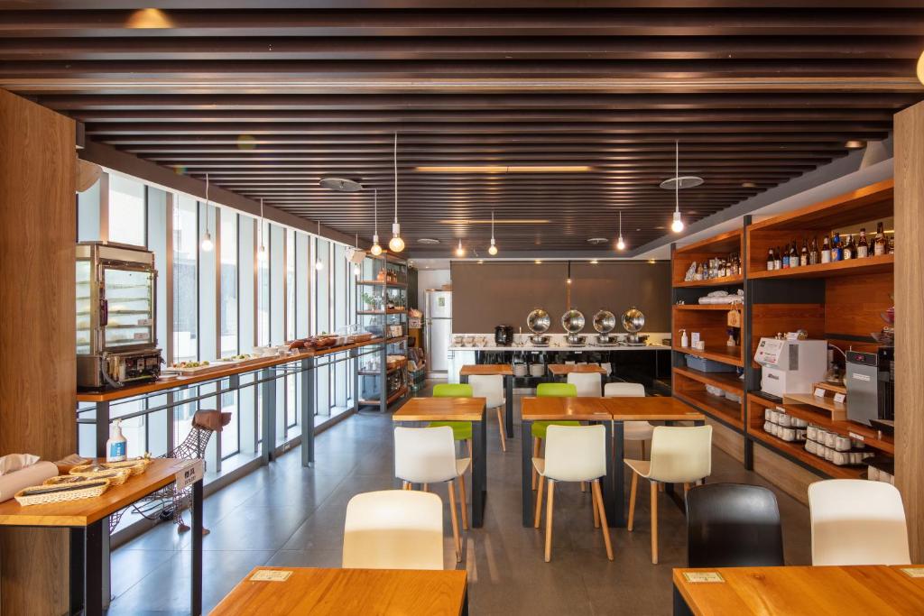 a restaurant with wooden tables and white chairs at Chaiin Hotel - Dongmen in Taipei