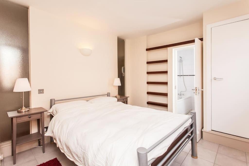 um quarto branco com uma cama e uma janela em Awesome apartment in the heart of Camden Town em Londres