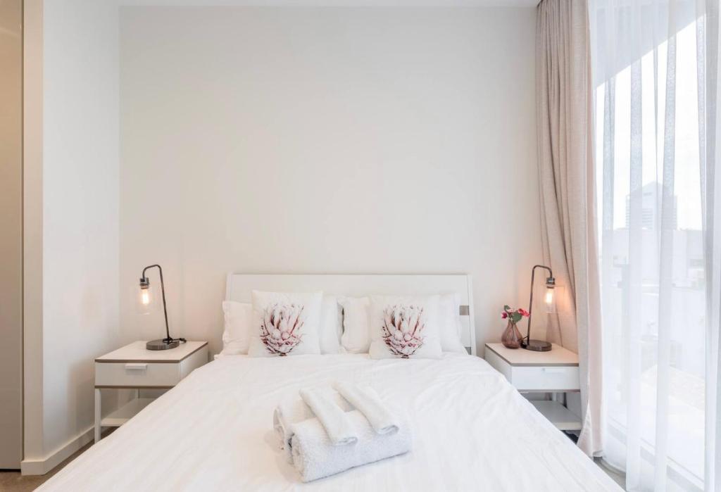 1 dormitorio blanco con 1 cama blanca y 2 toallas en Sydney CBD Modern 2 bedroom Apartment, en Sídney
