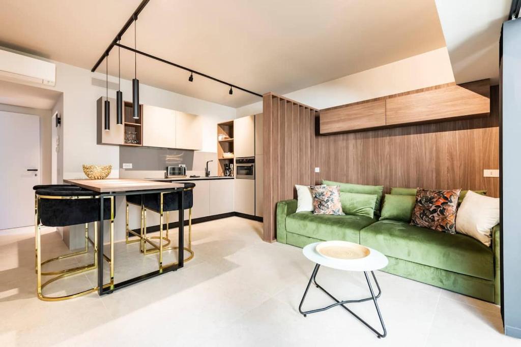 a living room with a green couch and a kitchen at LagoC0C00N - Colazione - 300m stazione - 800m lago in Desenzano del Garda