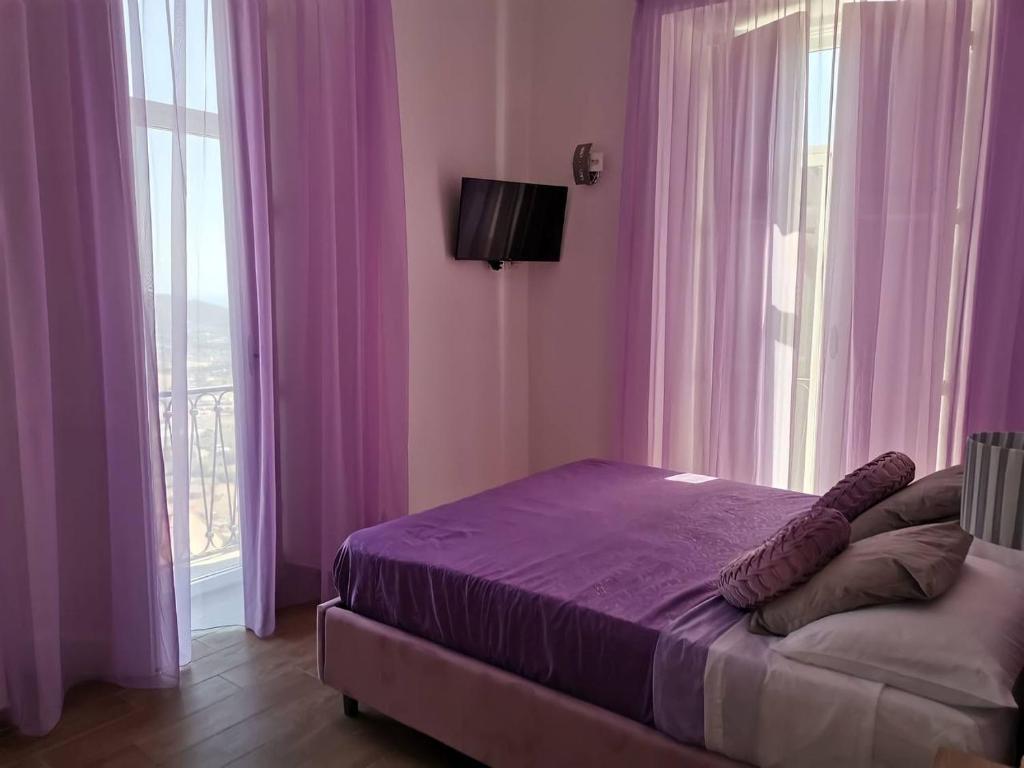 Un dormitorio con una cama con sábanas y ventanas púrpuras. en Antares Rooms en Castellabate