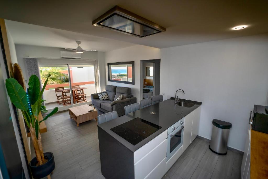 a kitchen and a living room with a couch at Apartasuites Royal Zahara, Máximo confort con vistas al mar in Zahara de los Atunes