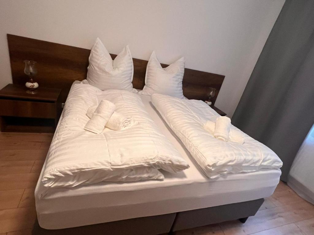 Una cama con sábanas blancas y almohadas. en Taverne & Pension Lubenbachtal, en Zella-Mehlis