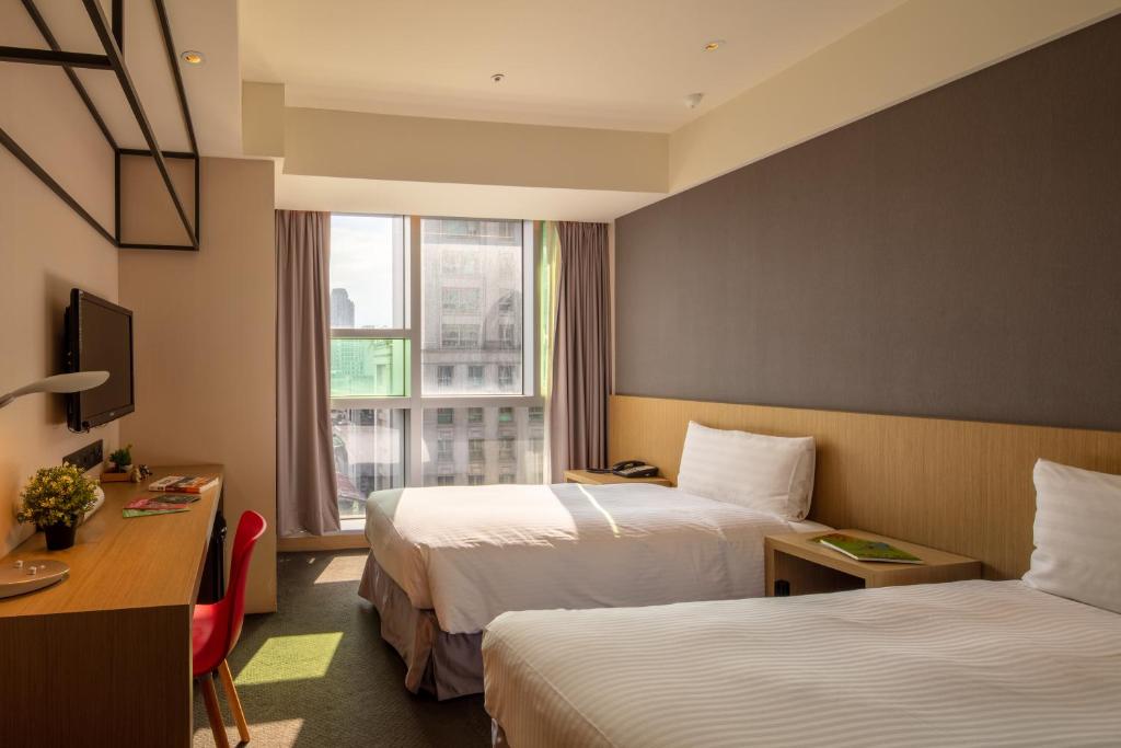 a hotel room with two beds and a window at Chaiin Hotel - Dongmen in Taipei