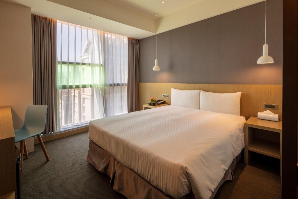 a hotel room with a large bed and a window at Chaiin Hotel - Dongmen in Taipei