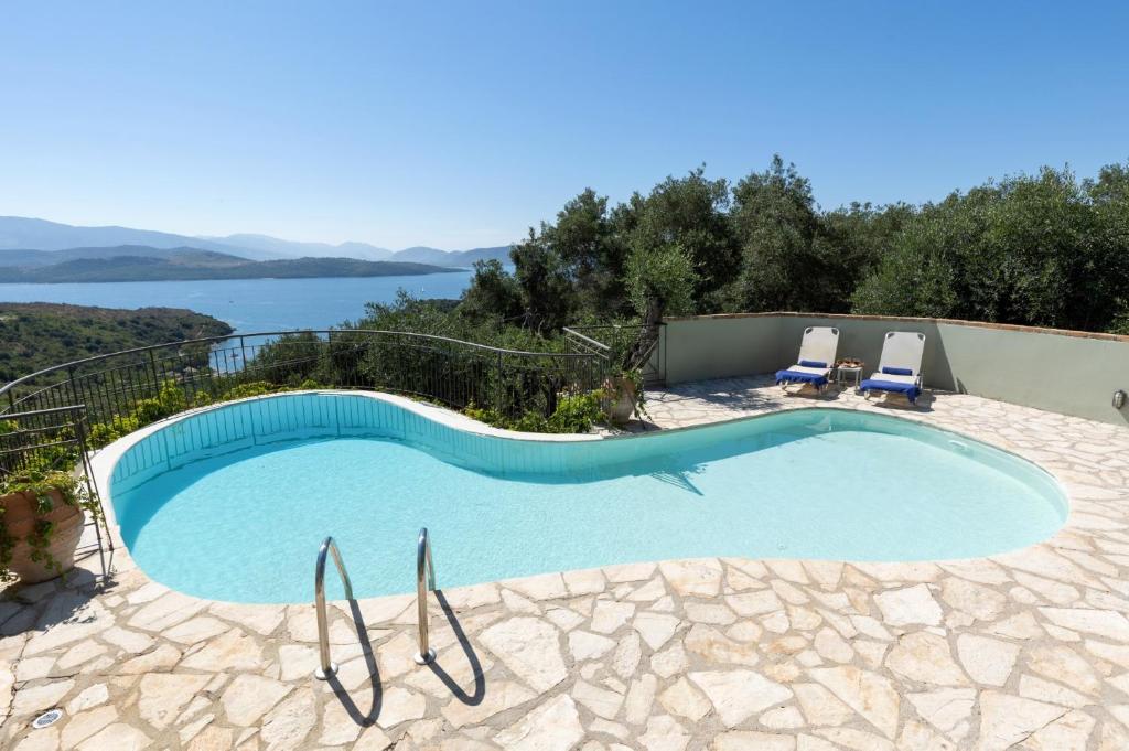 una piscina con 2 sillas y vistas al agua en Villa Firefly by Villa Plus en Ágios Stéfanos