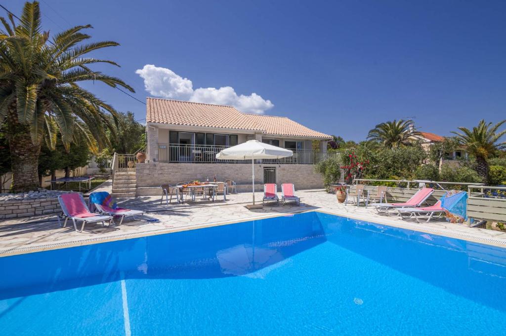 una piscina con sillas y una casa en Villa Petra by Villa Plus, en Ágios Stéfanos