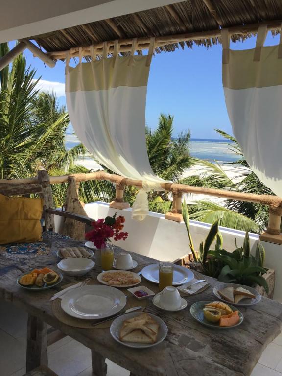 uma mesa com comida com o oceano ao fundo em Nakupenda Malaika Flat em Pwani Mchangani