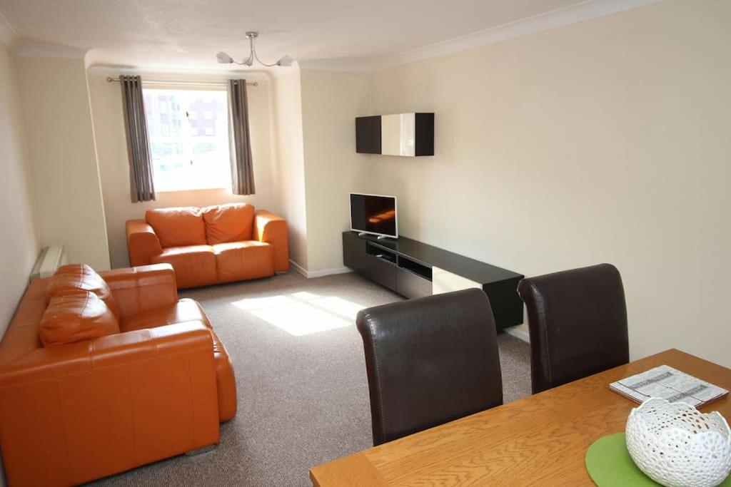 ein Wohnzimmer mit einem orangenen Sofa und einem Tisch in der Unterkunft Modern 2 bed flat on marina development! in Saint Peters