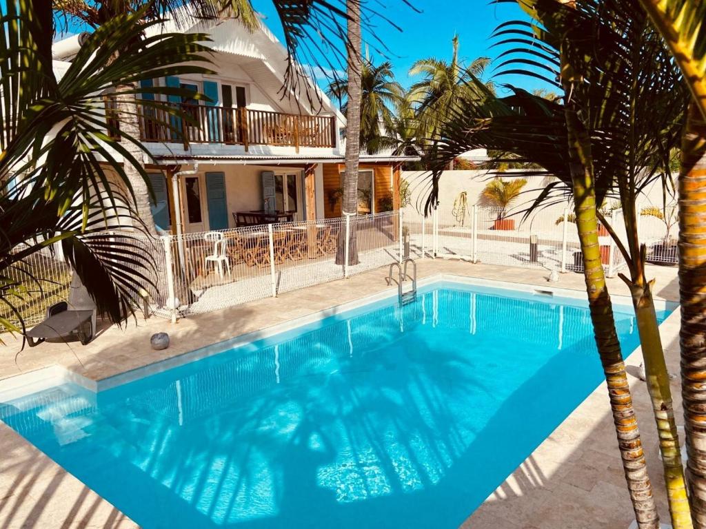 a swimming pool in front of a house with palm trees at LE NID TROPICAL in Étang-Salé les Bains