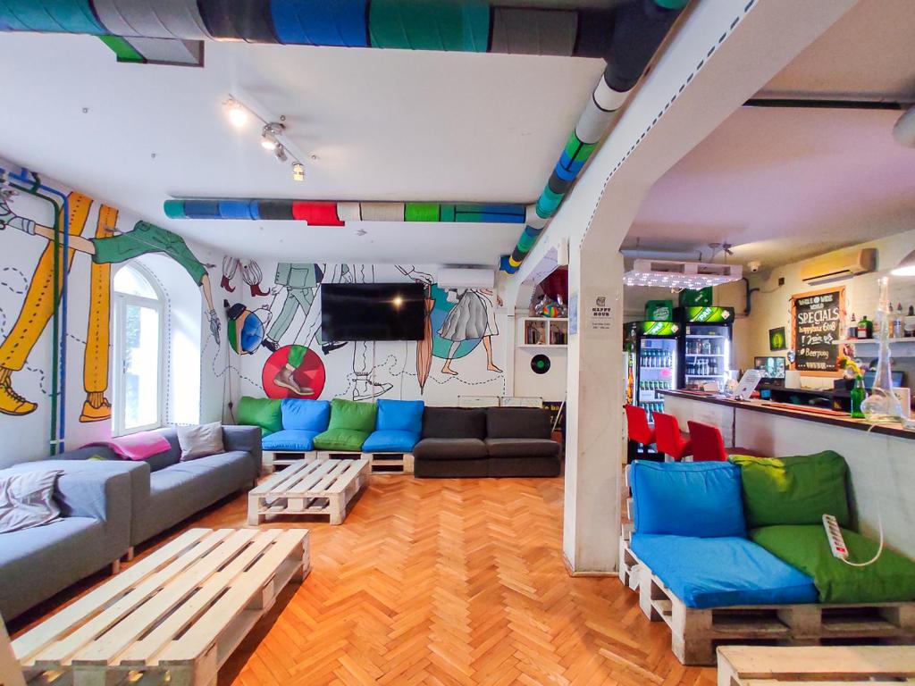 a living room with blue and green furniture and a kitchen at Whole Wide World Hostel in Zagreb