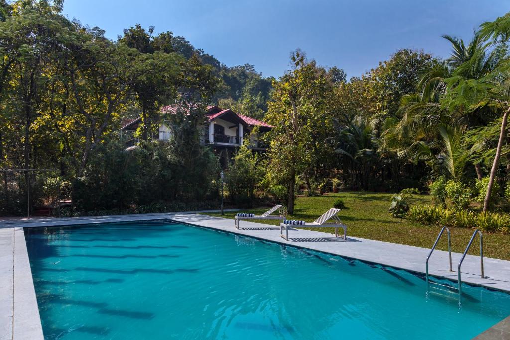 a swimming pool with two chairs and a house at SaffronStays Alma Grove, Kashid in Kashid