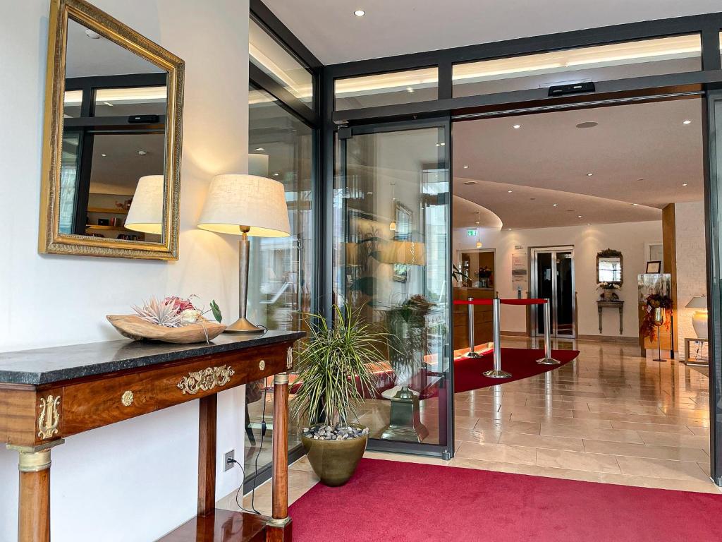 a lobby with glass walls and a table with a plant at Hotel-Restaurant Anne-Sophie in Künzelsau