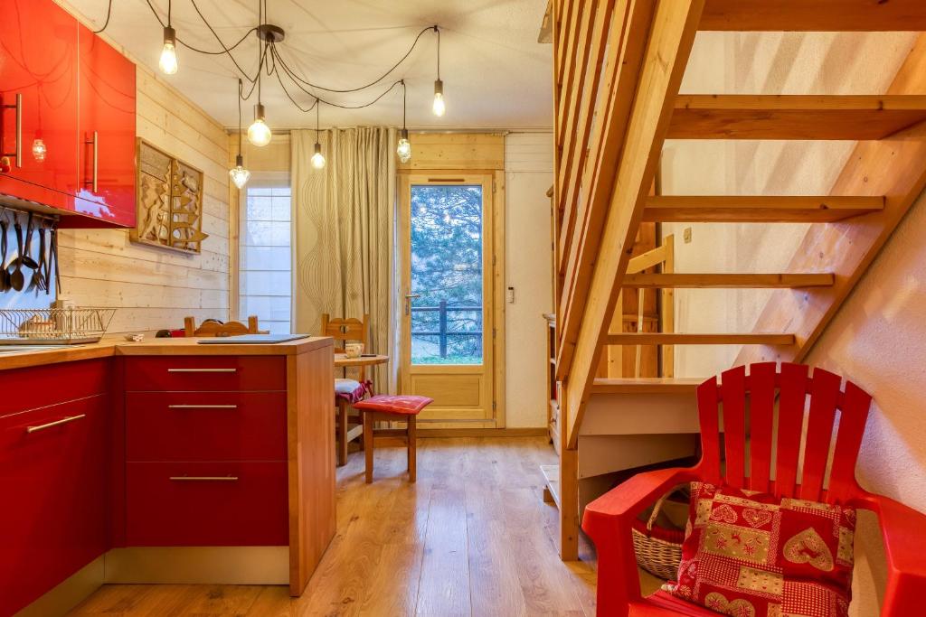 una cocina con armarios rojos y una escalera de caracol en Les Dolomites en Trièves, en Gresse-en-Vercors