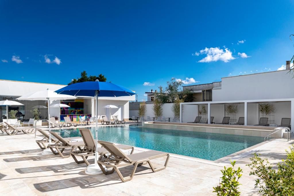 a pool with lounge chairs and an umbrella at Azzurra Aparthotel in Calimera