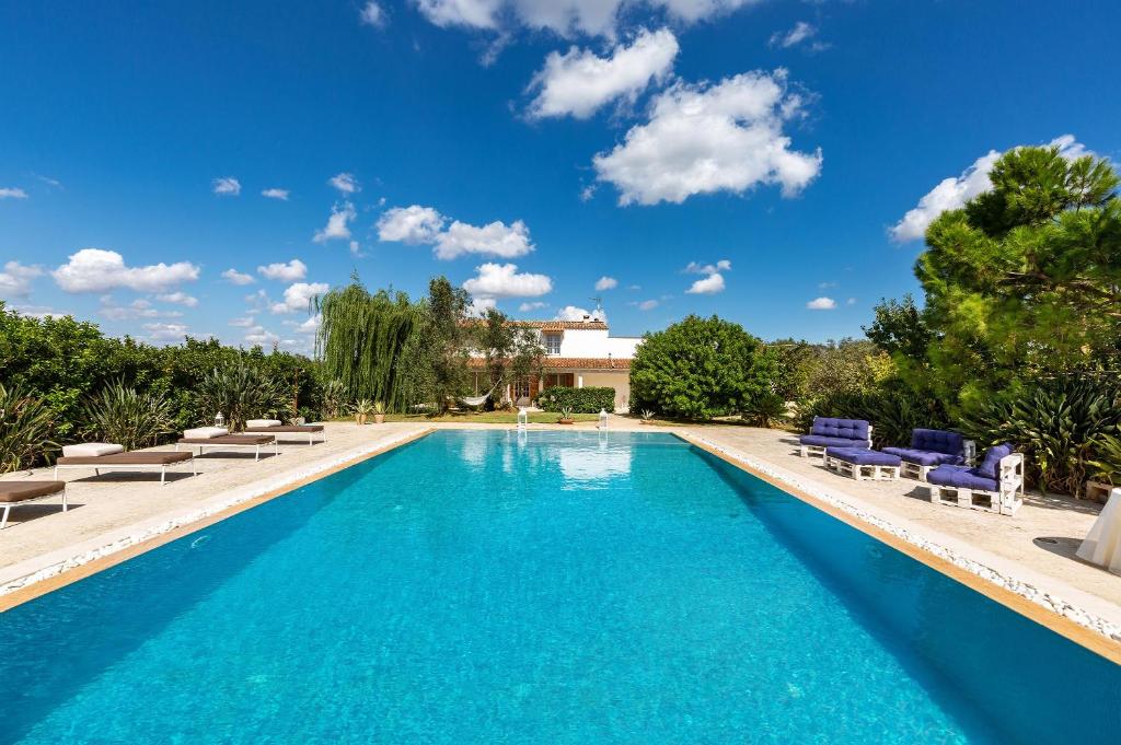a swimming pool with chairs and a blue sky at Villa Nina by Perle di Puglia in Zollino
