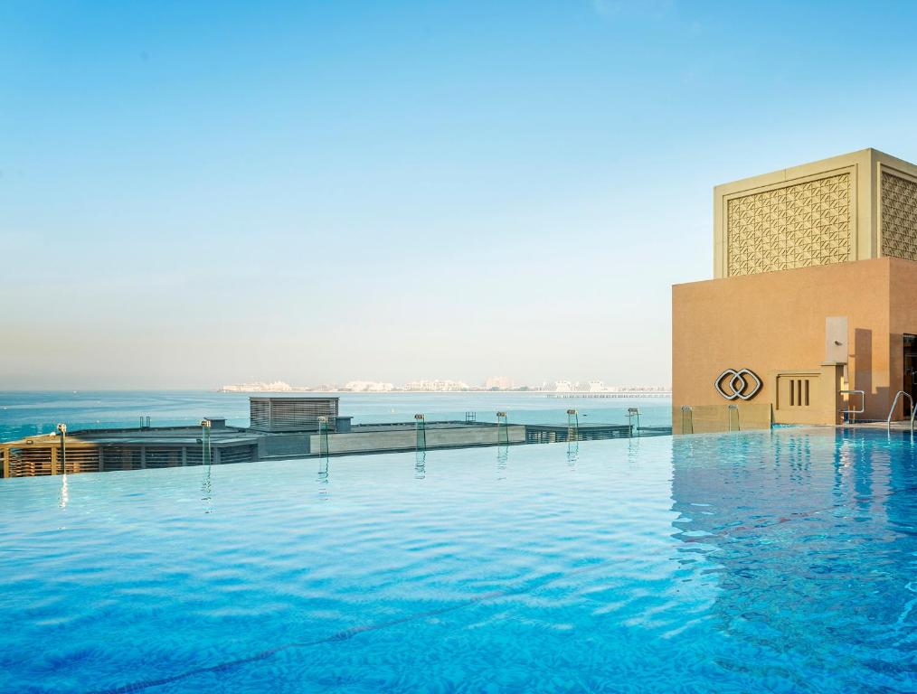 a large swimming pool next to a building with water at Sofitel Dubai Jumeirah Beach in Dubai