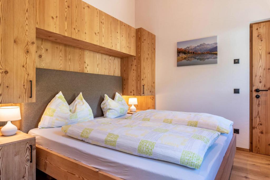 1 dormitorio con 1 cama grande y paredes de madera en Guntschöllerhof Mendelkamm, en Fiè