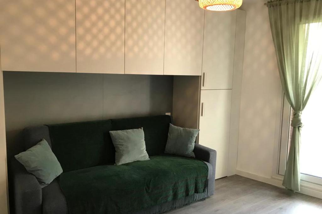 un sofá verde en una sala de estar con ventana en Design studio terrace and beach LIVE IN MARLYNE, en Cannes