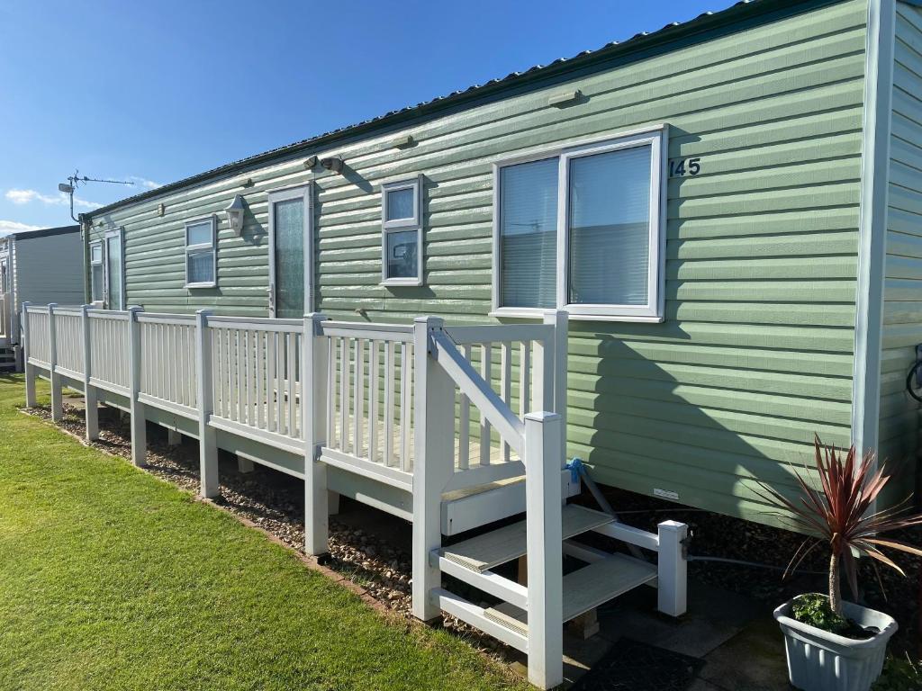 a green caravan with a porch and a fence at Seaview - 145 - Ingoldmells in Ingoldmells