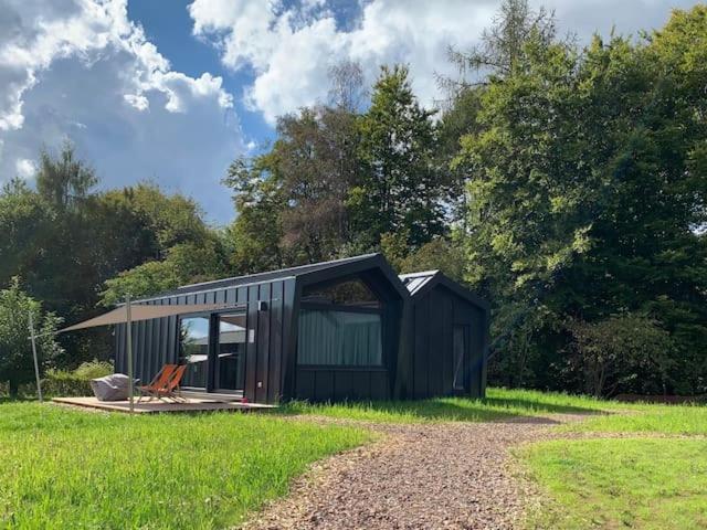 a black shed with a bench in the grass at Wellnester Tiny Houses and Retro-Caravan by the lake in Losheim am See in Losheim