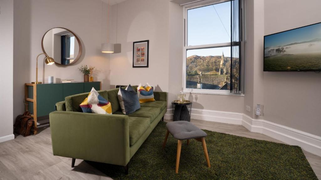 ein Wohnzimmer mit einem grünen Sofa und einem Fenster in der Unterkunft Calm - 1BR - 1BA - Apartment - Central Ambleside in Ambleside