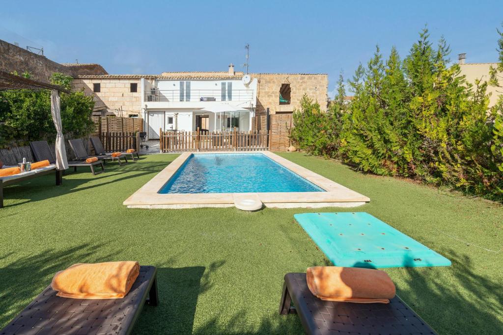 a backyard with a swimming pool with two loungers and a house at Can Miquel Porro in Llubí