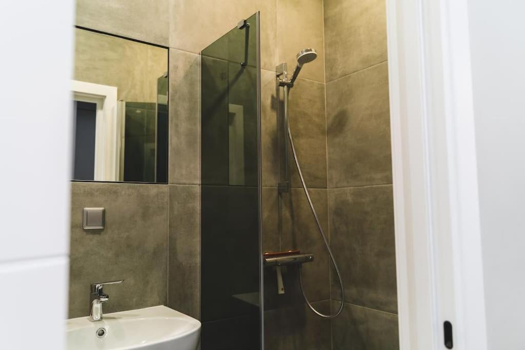 a bathroom with a shower with a sink and a mirror at Stylish flat in Rīga