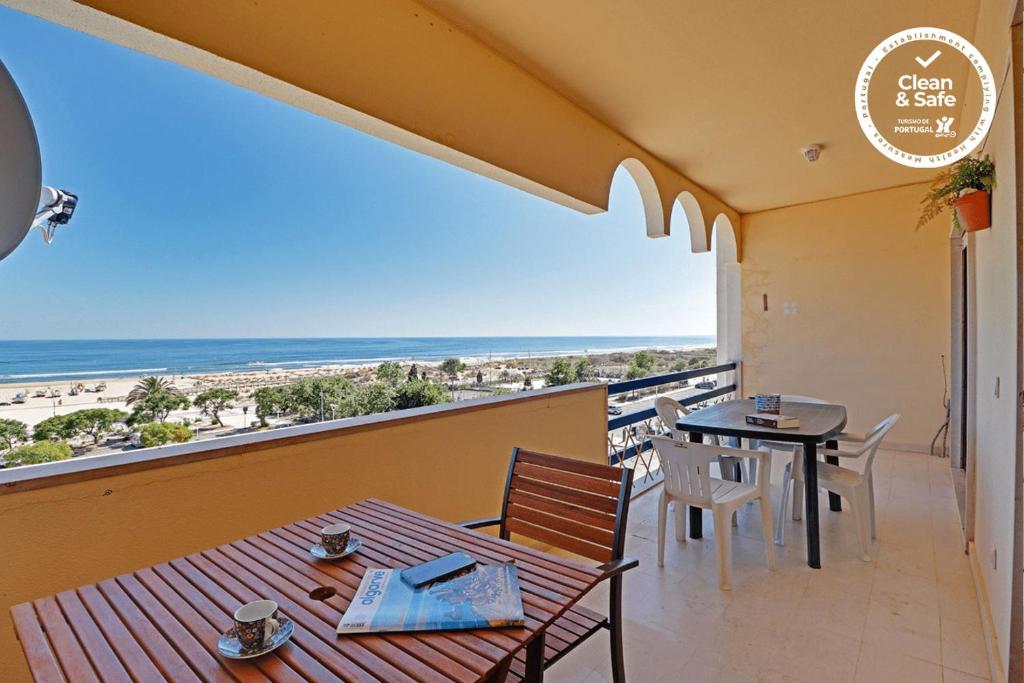 een balkon met een tafel en stoelen en uitzicht op het strand bij Monte Gordo Beachview 2 by Homing in Monte Gordo