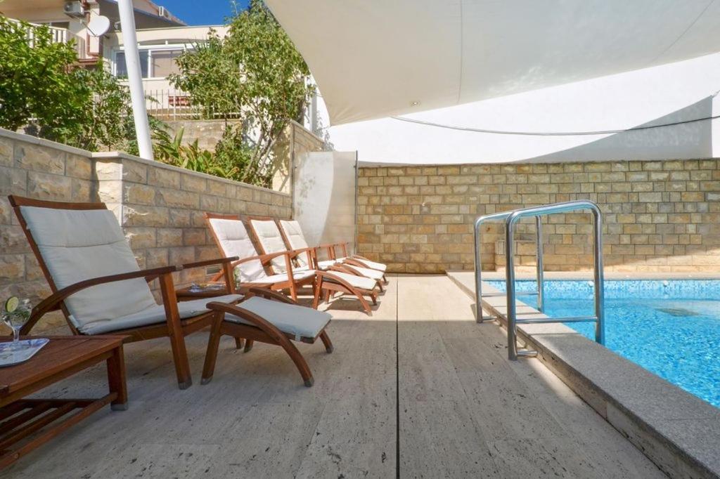 a patio with two chairs and a swimming pool at Apartment in Seget Vranjica with sea view, balcony, air conditioning, WiFi 91-2 in Seget Vranjica