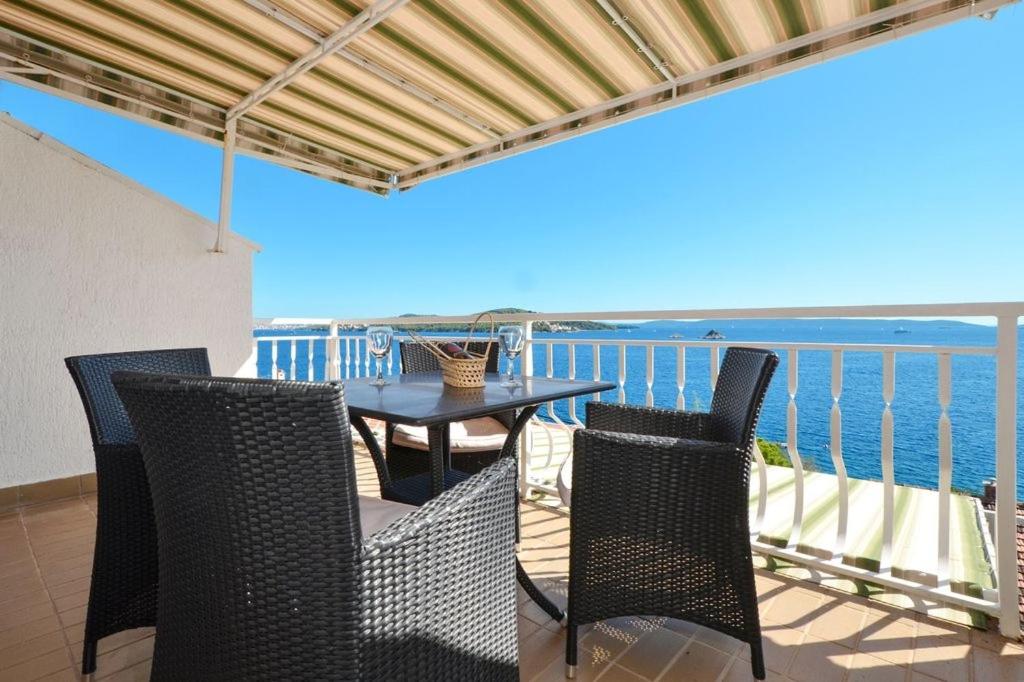 a table and chairs on a balcony with the ocean at Apartment in Seget Vranjica with sea view, balcony, air conditioning, WiFi 91-2 in Seget Vranjica