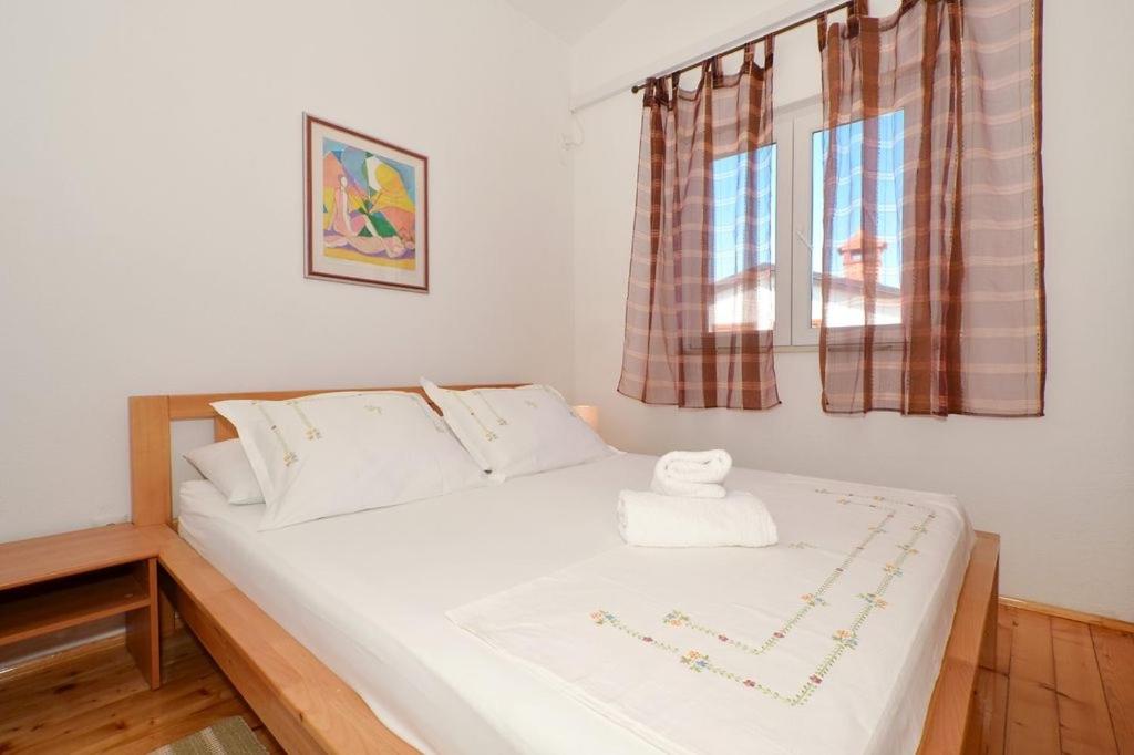 a bedroom with a white bed with two windows at Apartment in Seget Vranjica with sea view, balcony, air conditioning, WiFi 91-2 in Seget Vranjica