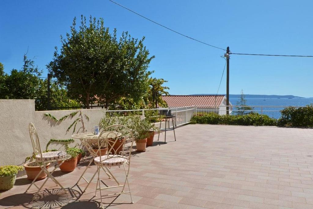 a patio with chairs and a table and plants at Apartment in Seget Vranjica with sea view, balcony, air conditioning, WiFi 91-2 in Seget Vranjica