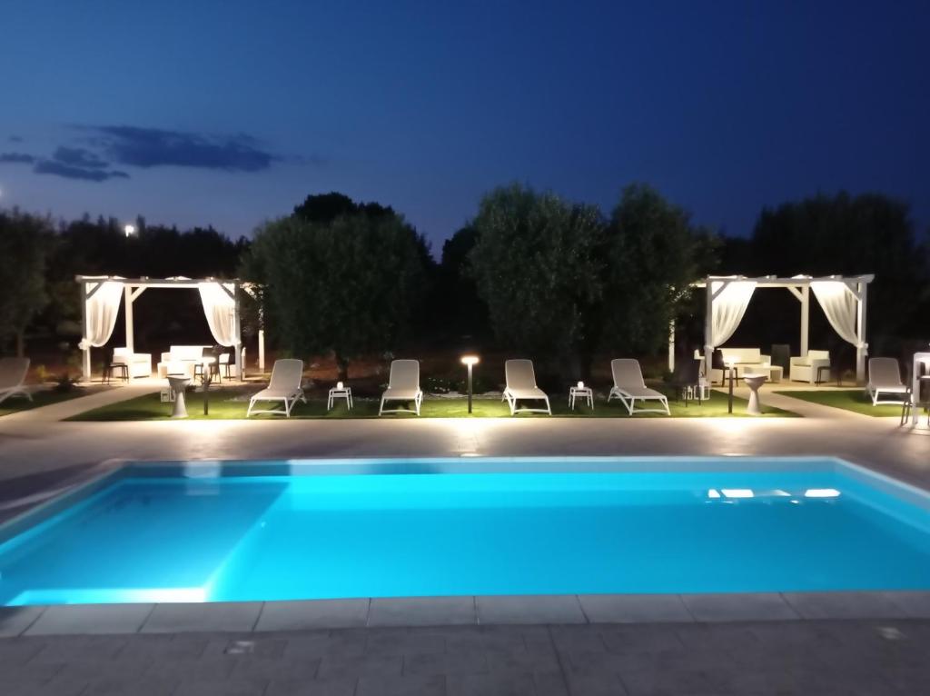ein Pool mit Stühlen und Sonnenschirmen in der Nacht in der Unterkunft Dimora Pianelle in Crispiano