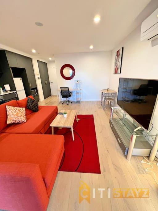a living room with a red couch and a television at Enchanting in Red - 1bd 1bth 1csp in Canberra
