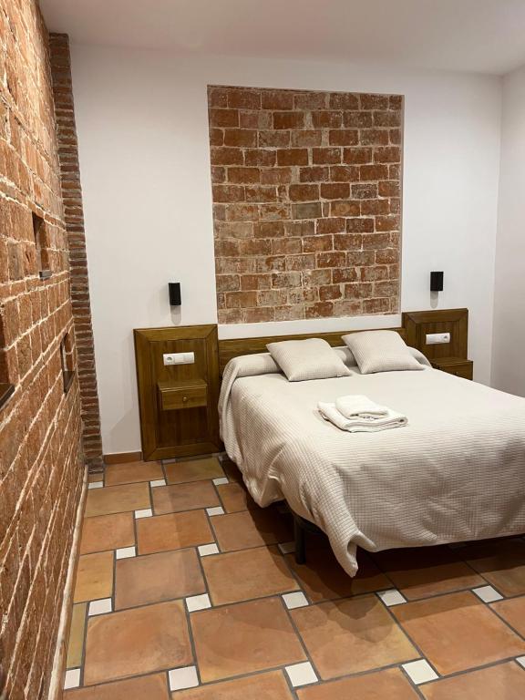 1 dormitorio con cama y pared de ladrillo en El Carmen en Benalúa de Guadix