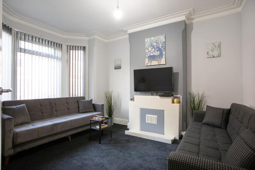 a living room with a couch and a flat screen tv at Cozy 3 bedroom house @ Hömli in Loughborough