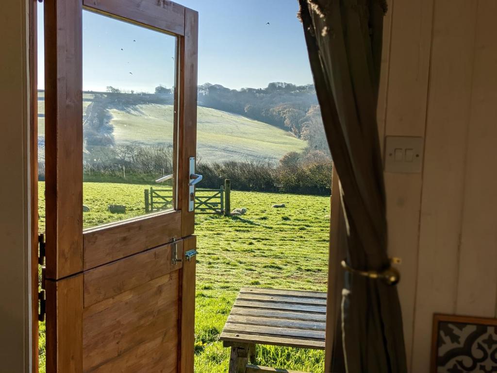 eine offene Tür mit Blick auf ein Feld in der Unterkunft Stunning Shepherd's Hut Retreat North Devon in Bideford
