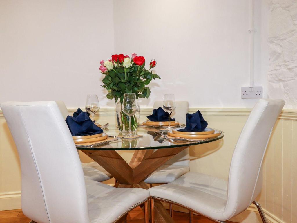 una mesa con sillas y un jarrón de flores. en Carew Lodge & Loft, en Torpoint
