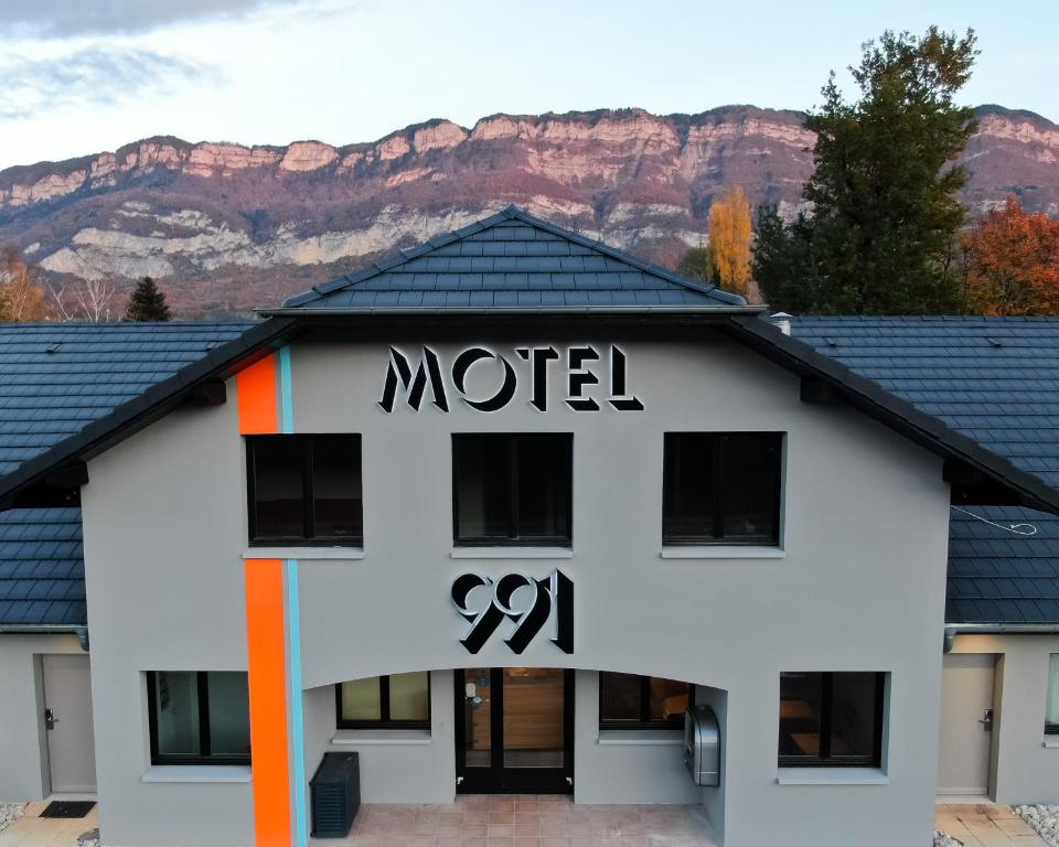 a motel with a sign on it with mountains in the background at Motel 991 in Viviers-du-Lac