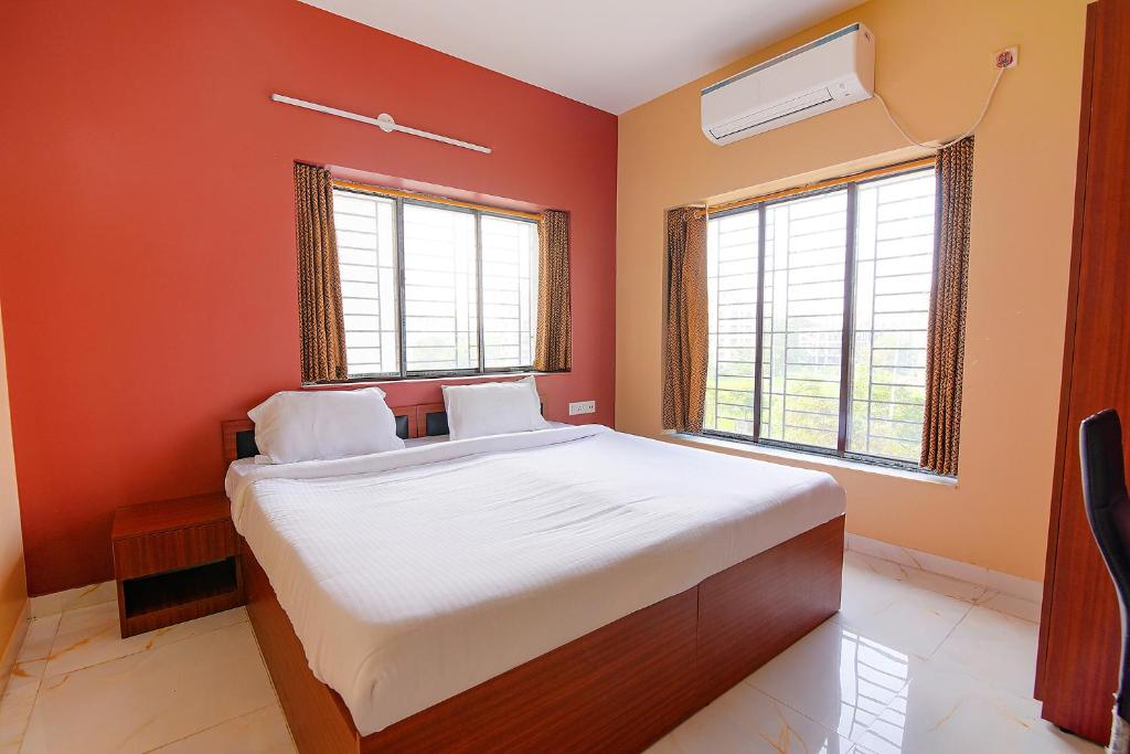 a bedroom with a bed with orange walls and windows at FabHotel Amar Raj Inn in Kolkata