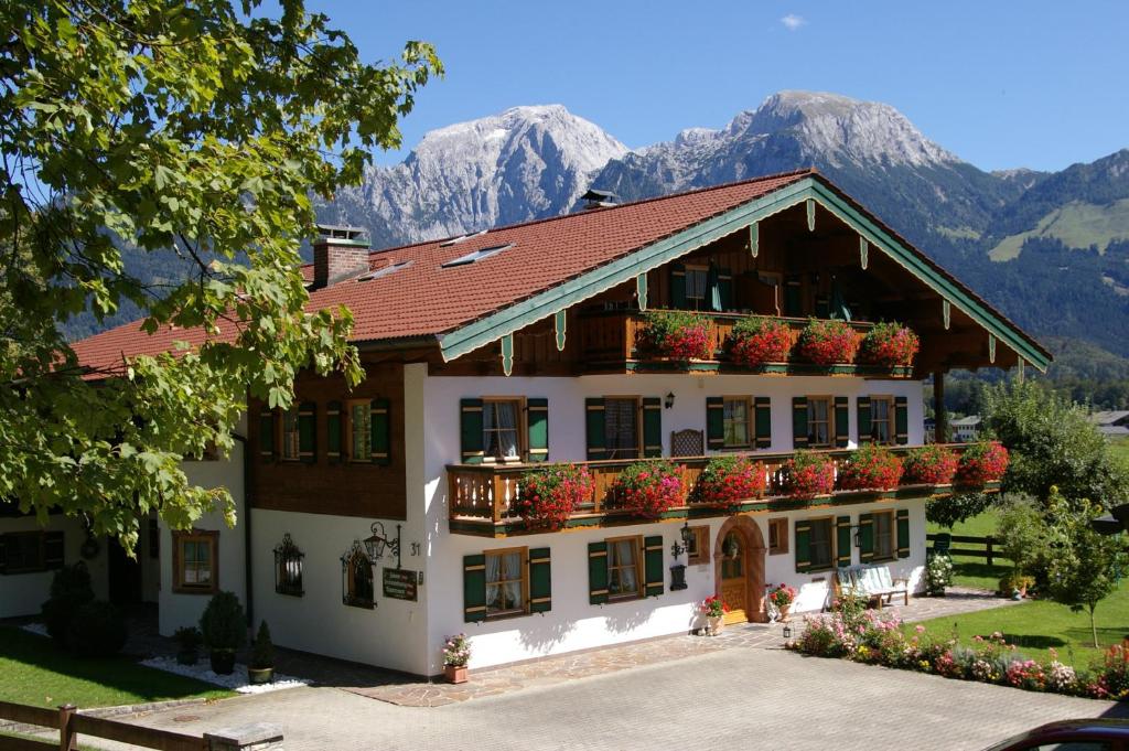 a building with flowers on the balconies and mountains at Gästehaus Almblick in Schönau am Königssee