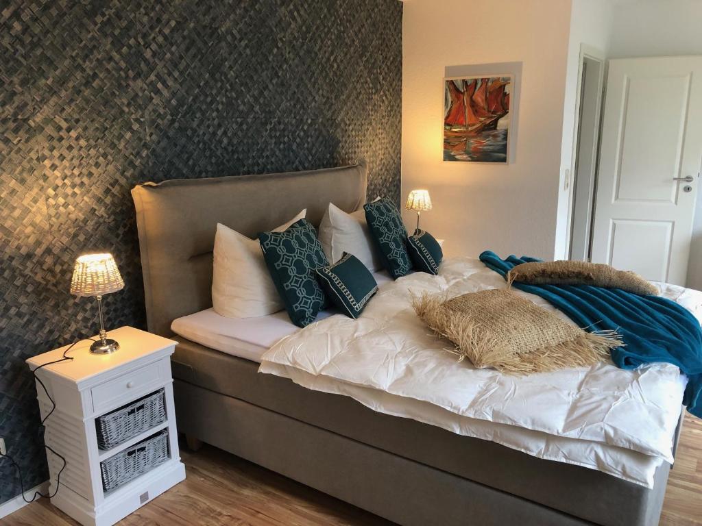 uma cama com almofadas azuis e brancas em romantisches Ferienhaus Boddenblick mit Sauna em Pruchten