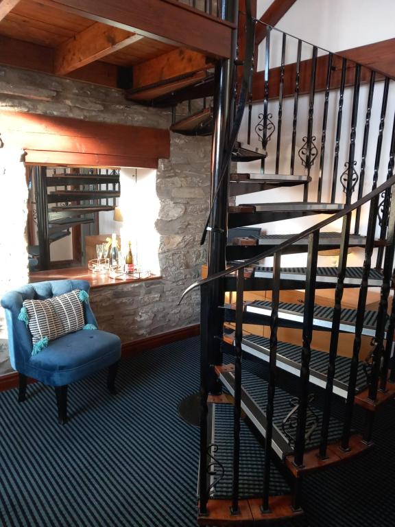 a spiral staircase in a room with a blue chair at Hayfellside Nook in Kendal