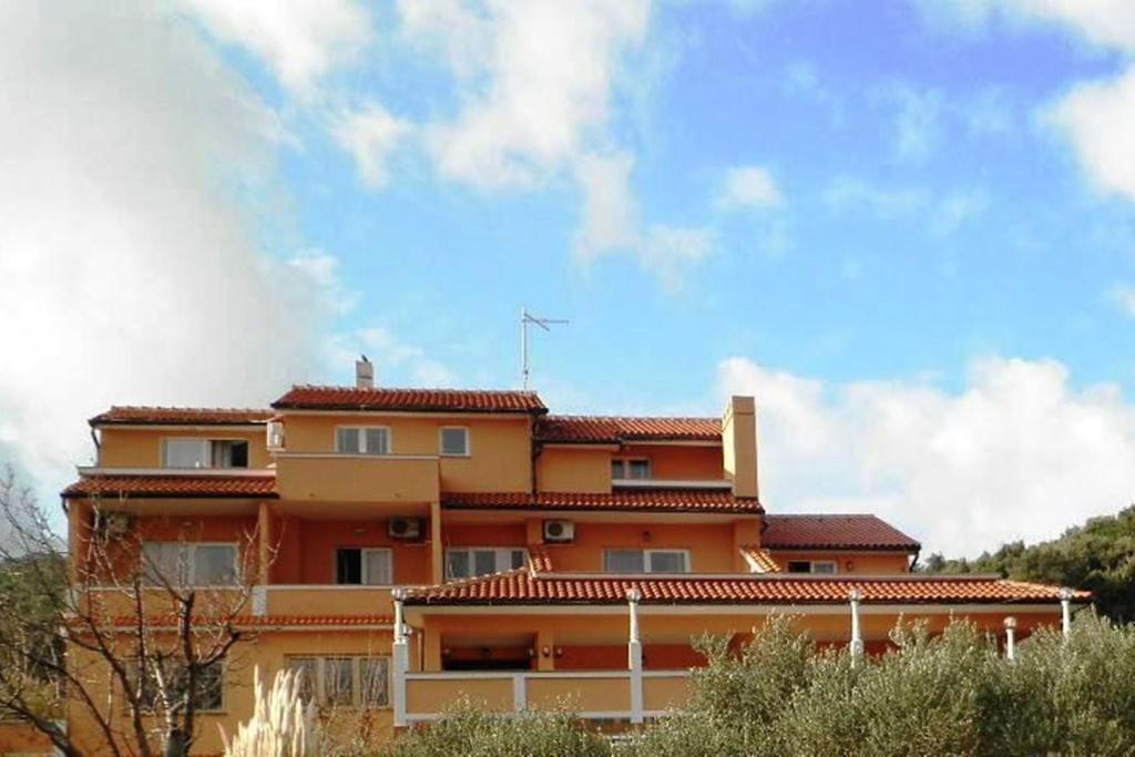 a large orange building with a sky in the background at Apartments Melita in Supetarska Draga